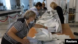 Members of an electoral commission empty a ballot box at a polling station following a referendum on the joining of Russian-controlled regions of Ukraine to Russia, in Sevastopol, Crimea, Sept. 27, 2022. 