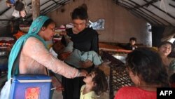 A health worker administers polio vaccine drops to a child during a vaccination campaign in Lahore, Pakistan, October 24, 2022. 
