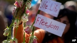 A protester holds roses with little hearts painted on them as she joined thousands in a show of support for Iranian protesters in The Hague, Netherlands, Oct. 8, 2022.