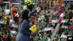 Holly Harmon places a rose into a memorial for victims of Hurricane Ian in Fort Myers, Fla., on Oct. 10, 2022. More than 100 died during the hurricane, with the greatest number in Lee County.