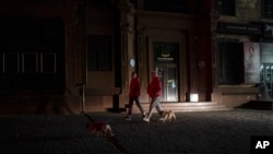 People walk with their dogs on a street in Zaporizhzhia, Ukraine, Oct. 19, 2022. 