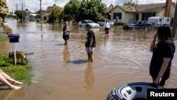 Local residents wade through floodwaters as the state of Victoria faces an ongoing flood crisis, in Shepparton, Australia, Oct. 16, 2022. (AAP Image/Diego Fedele via Reuters) 