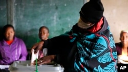 A woman covered with a blanket casts her vote at a poling station in Maseru, Lesotho, Oct. 7, 2022. 
