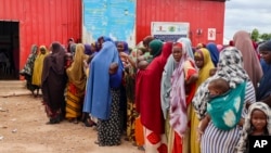 FILE - Somali women and children who left rural areas due to drought receive nutritional assistance at a camp for the internally displaced, on the outskirts of Baidoa, Somalia, Oct. 12, 2022.