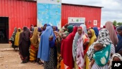 FILE - Somali women and children who left rural areas due to drought receive nutritional assistance at a camp for the internally displaced, on the outskirts of Baidoa, Somalia, Oct. 12, 2022.