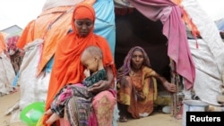 A Somali woman affected by the worsening drought due to failed rain seasons holds her daughter, 3, as her grandmother looks on, outside their makeshift shelter at the Alla Futo camp for internally displaced people, on the outskirts of Mogadishu, Somalia, Sept. 23, 2022.