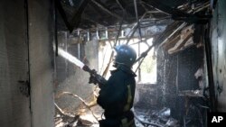 A firefighter works at the site of the burning after shelling in Donetsk, the capital of Donetsk People's Republic, eastern Ukraine, Oct. 16, 2022. 
