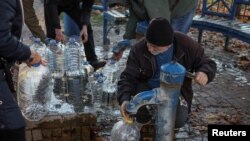 A man fills a container as local residents queue for water after about 80% of the Kyiv's inhabitants were left without water, after a Russian missile attack, Oct. 31, 2022. 