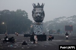 Pengendara motor mudik di luar Stadion Kanjuruhan pada pagi hari usai pertandingan sepak bola antara Arema FC dan Persebaya Surabaya di Malang, Jawa Timur, 2 Oktober 2022. (Foto: AFP/Putri)