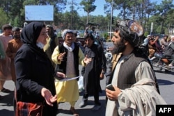 FILE - An Afghan woman speaks with a member of the Taliban during a protest in Herat, Sept. 2, 2022. Defiant Afghan women said they were willing to accept the all-encompassing burqa if their daughters could still go to school under Taliban rule.