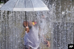 A member of an Australian cabaret and circus troupe cools down in a fountain on the South Bank in London, July 19, 2022.