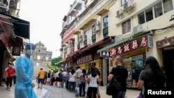 FILE - People line up to be tested for the coronavirus that causes COVID-19 near the Ruins of Saint Paul's in Macao, China, June 20, 2022.