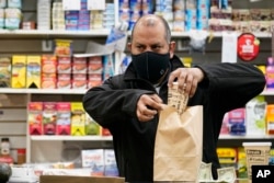 Pemilik Bodega Francisco Marte menyiapkan kopi untuk pelanggan, Rabu, 10 Februari 2021, di tokonya di wilayah Bronx, New York. (AP/Kathy Willens)