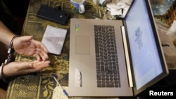 FILE - Members of the Security Service of Ukraine check the social media of a man suspected to be a Russian collaborator after he was detained at his home in Kharkiv, Ukraine, May 12, 2022.