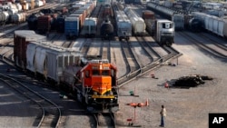 FILE - A BNSF rail worker monitors the departure of a freight train on June 15, 2021, in Galesburg, Illinois. 