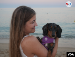 Sandra Azuaga posa junto a su perrita "Bruna" en la playa de Badalona, Barcelona, el 12 de julio de 2022.