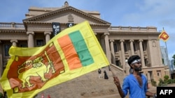 FILE - A man wears a headband with a slogan against interim Sri Lankan President Ranil Wickremesinghe as he waves the Sri Lankan national flag near the Presidential secretariat in Colombo, July 17, 2022. 