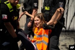 Police officers carry away climate activist Lina Schinkoethe during a protest with the group Uprising of the Last Generation at the chancellery in Berlin, Germany, Wednesday, June 22, 2022.