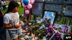 En esta foto de archivo tomada el 28 de mayo de 2022, una niña visita un monumento improvisado para las víctimas del tiroteo frente al juzgado del condado de Uvalde en Texas.