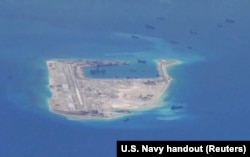 Chinese dredging vessels are purportedly seen in the waters around Fiery Cross Reef in the disputed Spratly Islands in the South China Sea in this still image from video taken by a P-8A Poseidon surveillance aircraft provided by the United States Navy.
