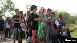 Migrantes que buscan asilo, en su mayoría de Venezuela y Cuba, esperan ser transportados por agentes de Aduanas y Protección Fronteriza de EEUU después de cruzar el río Bravo hacia EEUU desde México en Eagle Pass, Texas, el 13 de julio de 2022.