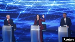 Simone Tebet, presidential candidate of the Brazilian Democratic Movement (MDB), raises her hand as Brazil's President Jair Bolsonaro, presidential candidate of the Liberal Party (PL), and Brazil's former president Luiz Inacio Lula da Silva look on during