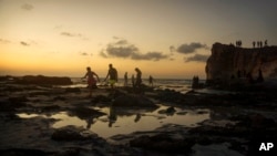 FILE - Egyptians on holiday walk at Cleopatra Beach, in the Mediterranean city of Marsa Matrouh, 270 miles (430 kilometers) northwest of the capital, Cairo, Egypt, Aug. 10, 2022. 