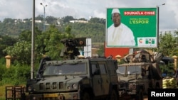 FILE - A convoy of peace keeping forces stand next to an electoral billboard of Soumaila Cisse, leader of URD (Union for the Republic and Democracy) opposition party during a patrol in Bamako, Mali, Aug. 9, 2018. 
