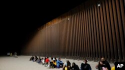 Migrantes esperando junto al final de un tramo de frontera el martes 23 de agosto de 2022 cerca de Yuma, Airzona.