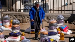 FILE - An Afghan man stands between food supplies during a distribution of humanitarian aid for families in need, in Kabul, Afghanistan, Feb. 16, 2022.