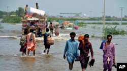 People wade through a flooded area of Sohbatpur, a district of Pakistan's southwestern Baluchistan province, Aug. 29, 2022.