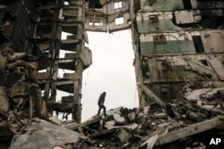 Seorang warga mencari barang-barang di gedung apartemen yang hancur saat pertempuran pasukan Ukraina dengan Rusia di Borodyanka, Ukraina, 5 April 2022. (Foto: AP)