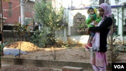 Moon Manisha stands with her son by the grave of her husband, Jony, a leader of the student wing of the opposition Bangladesh Nationalist Party. Jony's bullet-riddled body was found a day after he was allegedly abducted by police from Dhaka, Jan. 19, 2015. (Nazmul Haque/VOA)