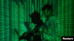 FILE - An illustration picture shows a projection of binary code on a man holding a laptop computer.