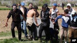 Мігранти несуть пораненого товариша в Ідомені