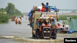 A family puts their belongings on a higher ground as they travel, following rains and floods during the monsoon season in Sohbatpur, Pakistan, Aug. 29, 2022.