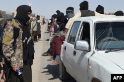 FILE - A Taliban fighter stands at a checkpoint between the borders of Afghanistan, Iran and Pakistan on the outskirts of Zaranj, Afghanistan, Feb. 17, 2022.