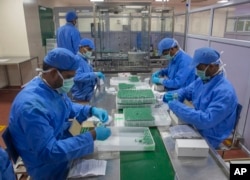 FILE - Employees pack boxes containing vials of Covishield, a version of the AstraZeneca vaccine, at the Serum Institute of India in Pune, Nov. 22, 2021.