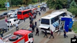 Police escort migrants to board a bus at the scene of an incident, in the Black Sea city of Burgas, Bulgaria, Aug. 25, 2022. (Bulgarian News Agency via AP)