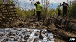Ukrainian forensic police officers look for shrapnel as they examine a crater following a missile strike in the Dokuchaievske village near Kharkiv, Aug. 21, 2022. 