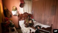 Duverseau Marie Cephta, whose leg was amputated when she was injured in last year's 7.2-magnitude earthquake, listens to news via a radio inside her home in the Lagodray area of Les Cayes, Aug. 19, 2022.