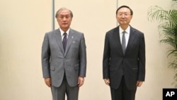 In this photo released by Xinhua News Agency, Yang Jiechi, right, a member of the Political Bureau of the Communist Party of China (CPC) Central Committee, poses for photos with Akiba Takeo, head of Japan's National Security Secretariat, in northern China, Aug. 17, 2022. 