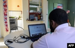 FILE - Cuban journalist Abraham Jimenez, manager of the independent information website "EL Estornudo," writes on his laptop at his house in Havana, Oct. 17, 2016.