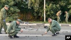 In this handout photo taken from video released by Investigative Committee of Russia on Aug. 21, 2022, investigators work on the site of explosion of a car driven by Putin Ally’s Daughter Daria Dugina outside Moscow. 