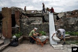 Volunteers clear rubble on the ground floor of Zhanna and Serhiy Dynaeva's house which was destroyed by Russian bombardment, in the village of Novoselivka, near Chernihiv, Ukraine, Aug. 13, 2022.
