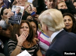 FILE - A woman blows a kiss to Republican presidential candidate Donald Trump (R) after Trump autographed her chest at his campaign rally in Manassas, Virginia, Dec. 2, 2015.