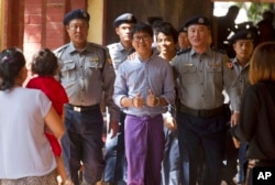 Reuters journalist Wa Lone, center, flashes thumps up as he is escorted by Myanmar police to court for trial, Feb. 1, 2018, on the outskirts of Yangon, Myanmar.