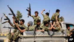 Shi'ite fighters ride on a patrol truck as they chant slogans during a tribal gathering showing support for the Houthi movement in Sana'a, Yemen, Dec. 14, 2015.