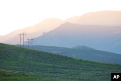 Power lines stand near hills outside Cody, Wyoming on Wednesday, June 15, 2022.