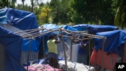 Women left homeless by last year's 7.2-magnitude earthquake create a frame for a makeshift shelter at Camp Devirel in Les Cayes, Haiti, Aug. 17, 2022. 